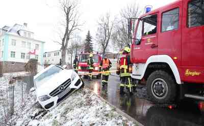 Eisglätte sorgt für Verkehrsunfall: Binnen Minuten winterliche Straßenverhältnisse, vermehrt Unfälle auf den Straßen, Mercedes rutscht von Straße in den Graben und droht umzukippen, Fahrerin kommt mit dem Schrecken davon: Kameraden der Feuerwehr sichern Fahrzeug mit Spanngurten, Kran von Abschleppwagen zieht Fahrzeug wieder auf Straße, Landschaftsaufnahmen