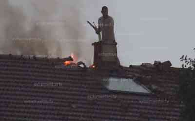 Schwere Unwetter in Bayern: Blitz schlägt in Mehrfamilienhaus ein, Anwohner steht selbst mit Strahlrohr auf dem Dach und löscht während des Unwetters, Menschen rennen vor den Unwettern in Sicherheit: Anwohner steht bei Blitzen im Hintergrund auf dem Dach und versucht sein Hab und Gut zu retten, Blitze am Abendhimmel, O-Ton Kreisbrandinspektor