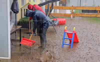 Schlammlawine zieht durch Ortschaft: Feuerwehr muss zahlreiche Sandsäcke verlegen um Mehrfamilienhaus vor Wasser zu schützen, schwere Technik im Einsatz, Kameraden füllen Sandsäcke im Bauhof: Anwohner: „Selbst durch das geschlossene Fenster ist das Wasser reingelaufen“, Feuerwehr im Dauereinsatz