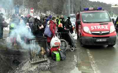 Ukrainekrieg-Eisige Kälte: chaotische Zustände an den Grenzen, Menschen sitzen mit Trainingshose vor Feuertonnen und wärmen sich auf (on tape), viele Flüchtlinge warten in eisiger Kälte auf Transportmöglichkeiten, Busse überqueren Grenze mit Flüchtlingen: Sammelplatz verschlammt, nur mit Minibussen können wenige Flüchtlingen zu größeren Sammelstellen gebracht werden, Busse mit Flüchtlingen überqueren Grenze