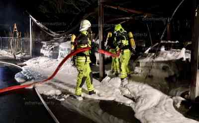 Carportbrand mit drei Fahrzeugen: Feuerwehr startet massiven Löschangriff bei eisiger Kälte, Feuerwehr kann Übergreifen auf Wohnhäuser verhindern: Alle drei Fahrzeuge brennen komplett aus Scheiben bersten an Wohnhäusern