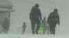 Schneeorkan im Erzgebirge: Orkanböen von bis zu 133 km/h, Schneesturm und white out am Fichtelberg, Menschen laufe mit Skiern auf Bundesstraße, null Sicht für Autofahrer: Menschen und Kinder im Schneeorkan auf dem Fichtelberg